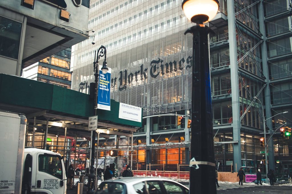 Street view of the New York Times Building in Manhattan with bustling city life and vehicles.