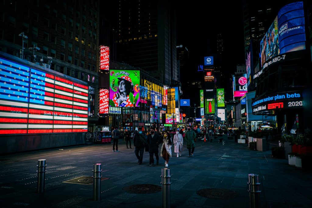 Vibrant nighttime scene in Times Square, NYC, with illuminated billboards and people walking.